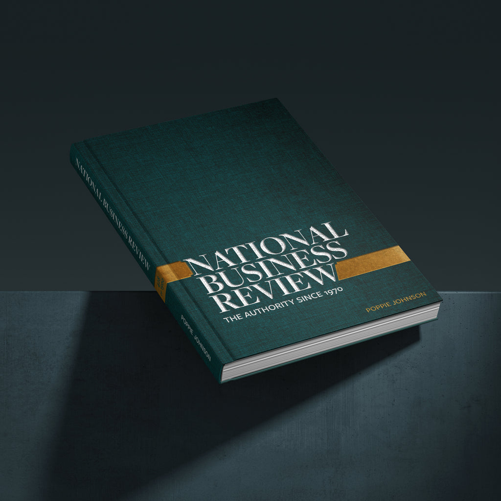 National Business Review book with a dark teal-green cover, gold accent band, and white title text, shown floating at an angle on a dark studio background.