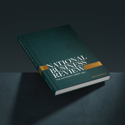 National Business Review book with a dark teal-green cover, gold accent band, and white title text, shown floating at an angle on a dark studio background.